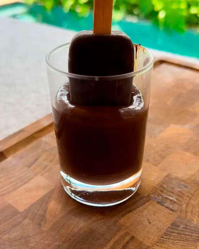 Paleta helada con cobertura oscura sobre un vaso