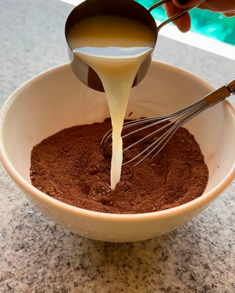 Ingrediente líquido vertiéndose sobre una mezcla en un recipiente