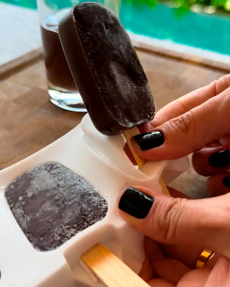 Manos desmoldando una paleta helada de chocolate