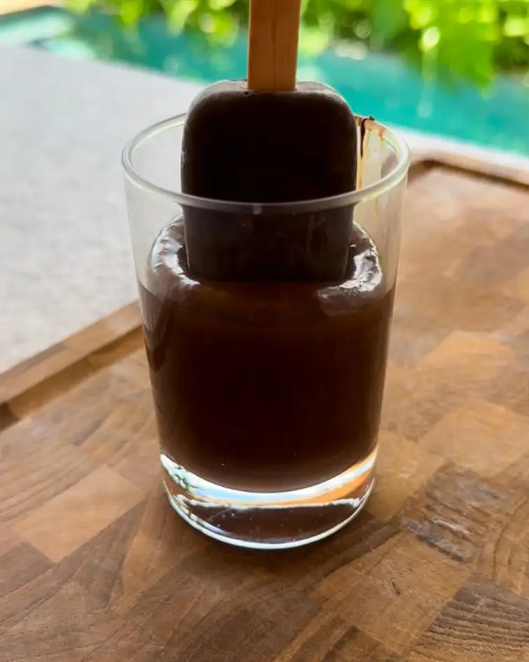 Paleta helada cubierta de chocolate colocándose en un vaso